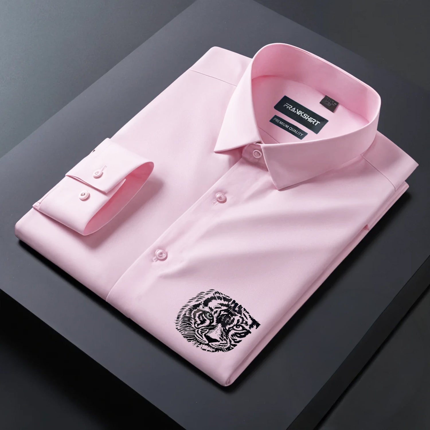 Folded pink dress shirt with a tiger emblem on a dark surface