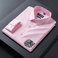 Folded pink dress shirt with a tiger emblem on a dark surface