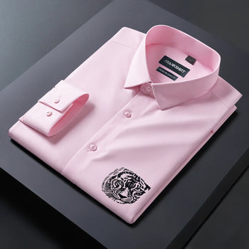 Folded pink dress shirt with a tiger emblem on a dark surface