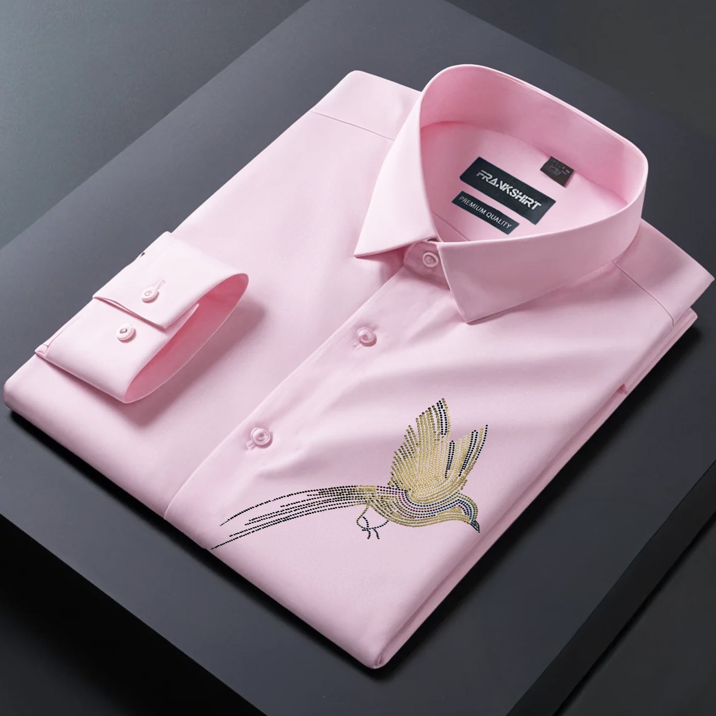 Pink dress shirt with bird embroidery on a dark surface