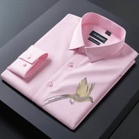 Pink dress shirt with bird embroidery on a dark surface