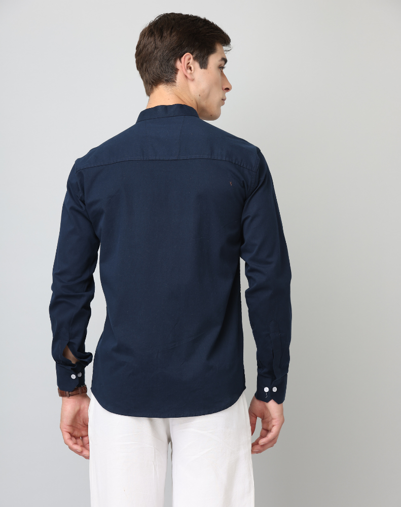 Man wearing a navy blue shirt and white pants on a gray background