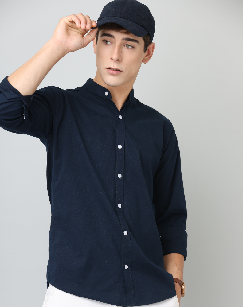 Man wearing a navy blue shirt and cap against a gray background