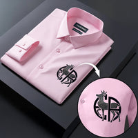 Pink dress shirt with a brand logo on a dark surface, showing a close-up of the logo.