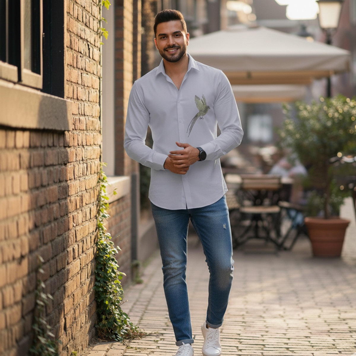 Man standing outdoors near a brick wall with a casual pose